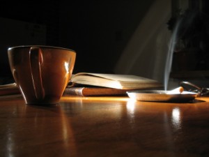 coffee lit cigarette and book on dark background to signify early morning