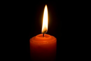 lit candle in dark room 