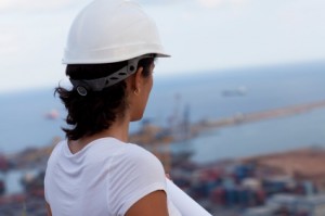 Woman in white hard hat looking at harbor