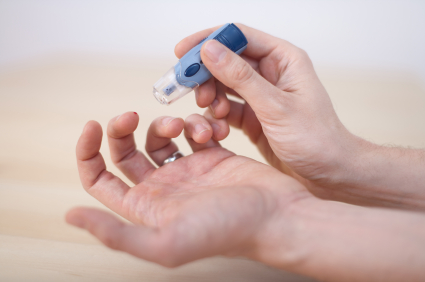 close up of man's hands giving himself a blood sugar test pricking finger