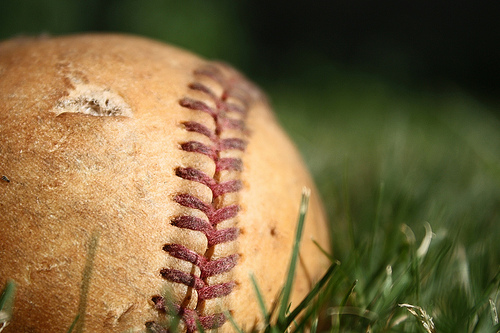 Old tattered baseball in field of grass lonely