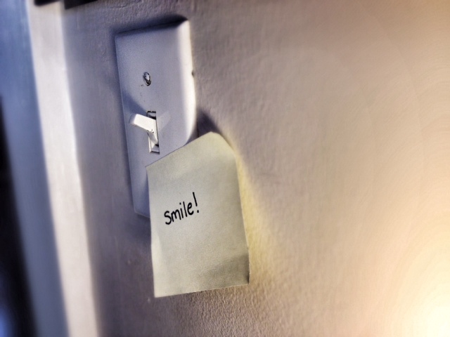 smile written on post it note on light switch