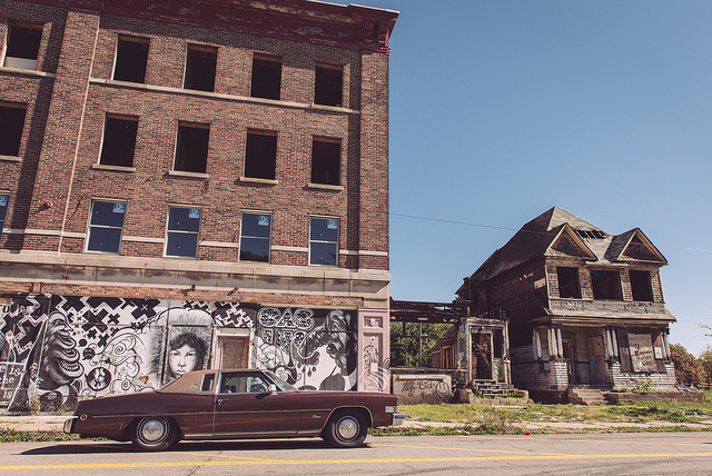 blighted business and home in detroit with old car in front