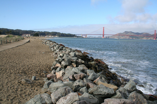 view of golden gate from crissy field with beach, path and rocks