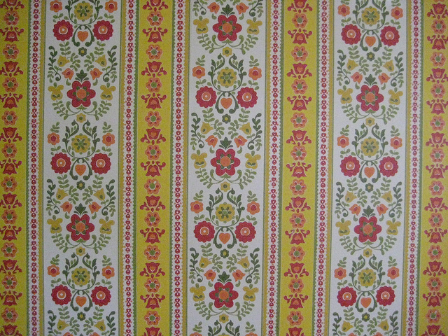 close up of patterned wallpaper pink flowers with green stems on white and yellow background