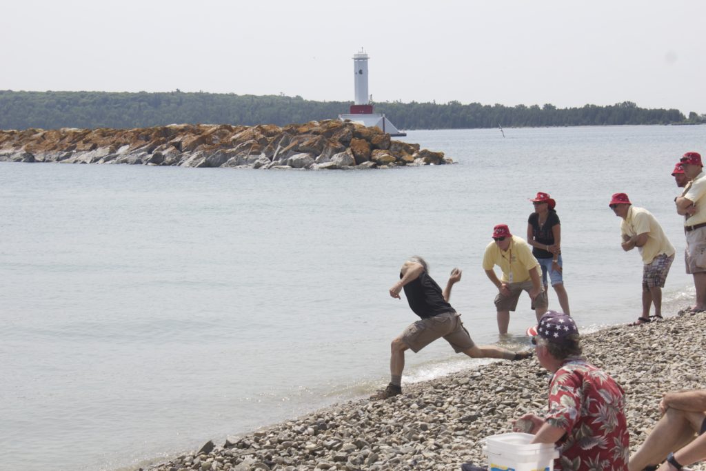 The actual competition, men tossing stones on shore