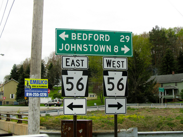 Road signs for route 56 east to bedford 29 miles west to johnstown 8 miles