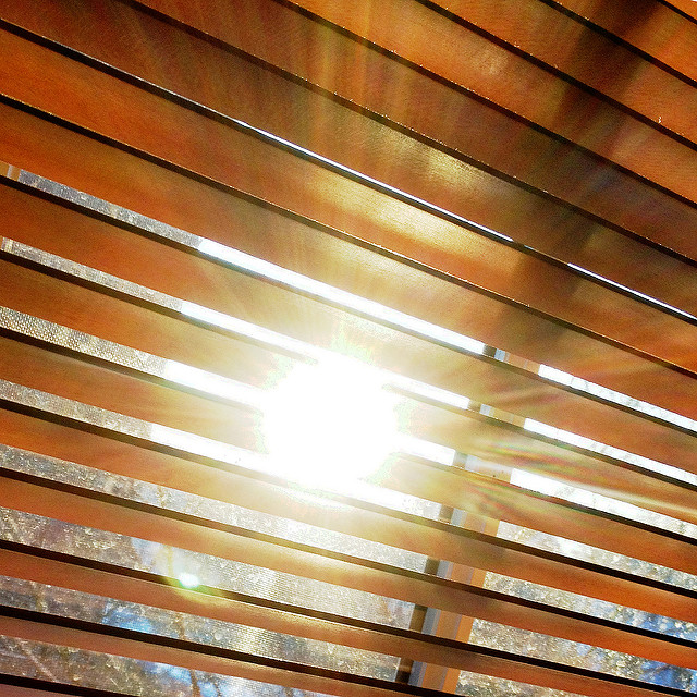 Sun shining through closed mini blinds on window
