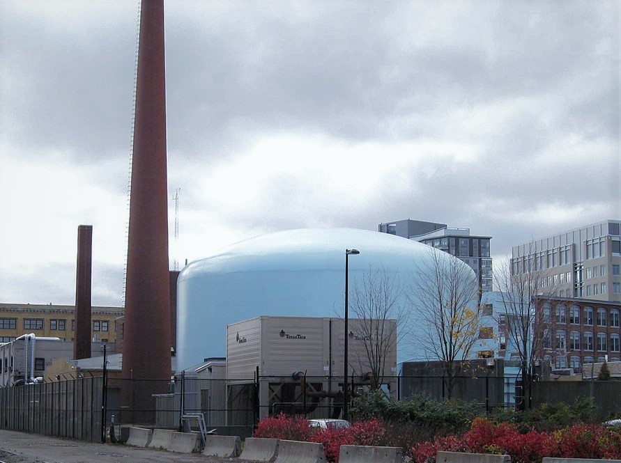 Power plant bubble looking building with tall smoke stack next to it industrial complex