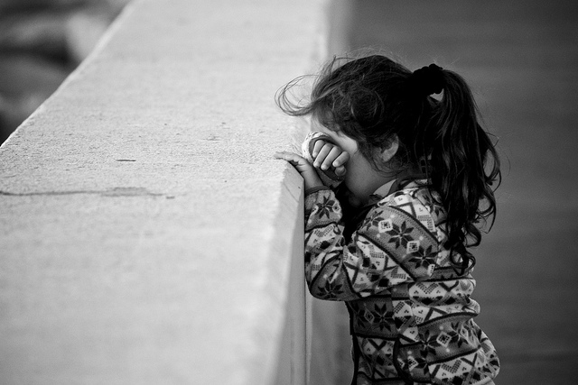 little girl with head down on wall as if counting for hide and seek game