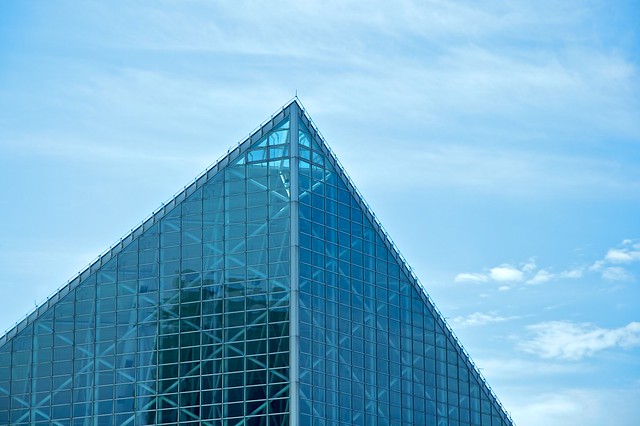 top of building (aquraium) made of glass, forming a point - blue sky behind