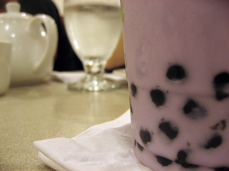 Close up of a bubble tea cup pink tea with the black squishy balls at the bottom