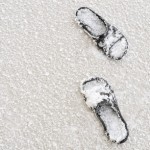 two sandals covered in snow, laying in the snow