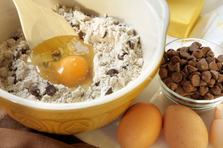 chocolate chip cookie ingredients mix and egg in a bowl with bowl of chips
