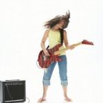 teenage girl playing eletric guitar with amp