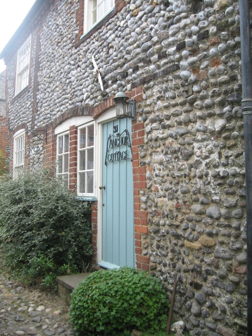 anchor cottage old stone building with robins egg blue door and name in iron