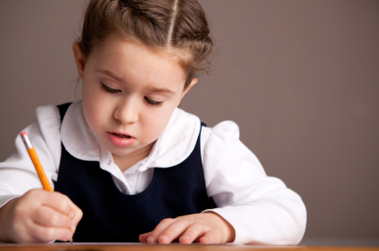 school girl in uniform writing at desk about 7 years old