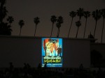 movie in cemetary with palm trees behind old film on screen