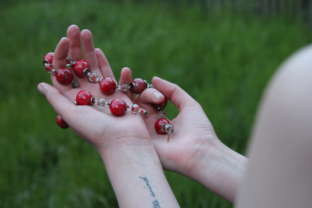 woman holding red glass bead necklace
