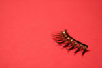 set of fake eyelashes for one eye right justifed over red background