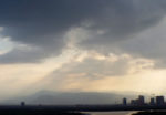 dark rain clouds and rain with a little light peeking through over city in UAE, mountains in distance