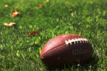 football on grassy field, a few fall leaves around
