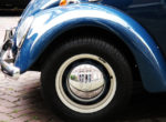 close up of blue VW wheel with reflection of building in hubcab