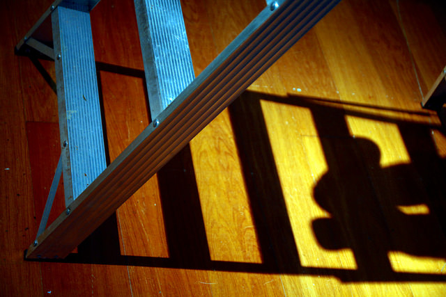 artistic shot of small ladder with shadow of ladder and feet off to side.