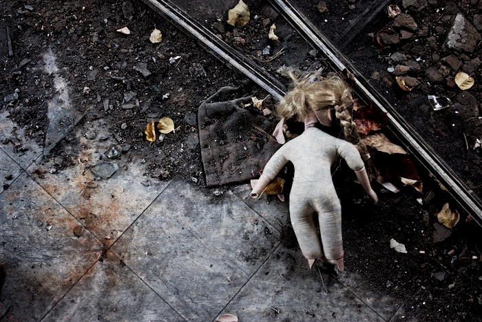broken female doll lying face down in dirt