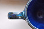 handmade ceramic mug, looking down at handle and half of mug; shiny blues and grees