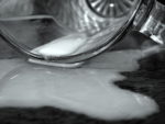 close up of glass on floor with milk spilling out