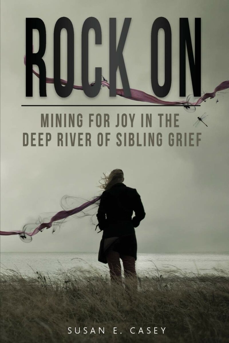 cover of rock on sibling grief - woman in field with back truned, looking at water