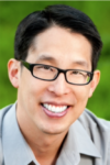 Headshot of Gene Luen Yang wearing black glasses