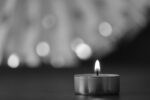 close up of lit tealight candle; blurry gray background