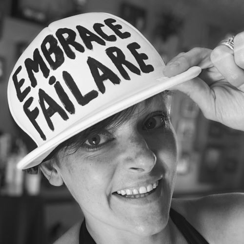 Leah lederman in hat that says embrace failare with the misspelling intentional for comedic effect