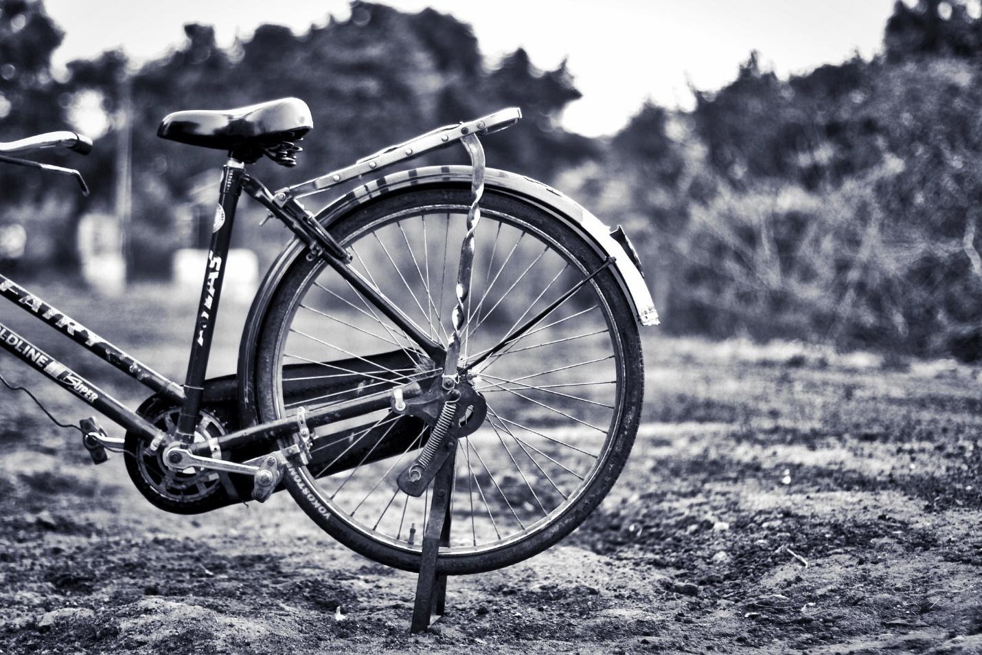 black and white image of a bike without wheels, parked in a field