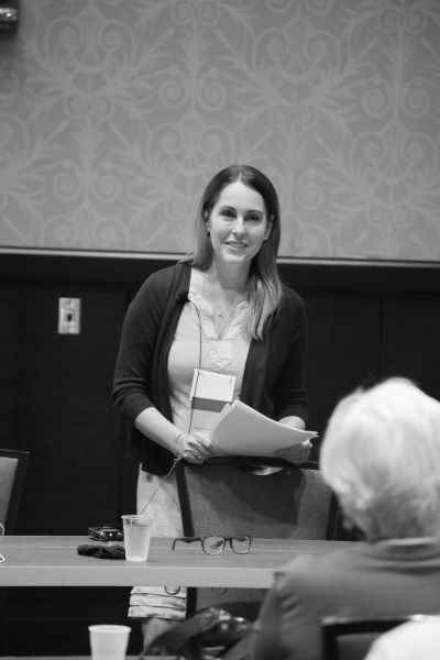 Jeannine Oullette presenting at HippoCamp 2021, front of room, smilng and holding papers