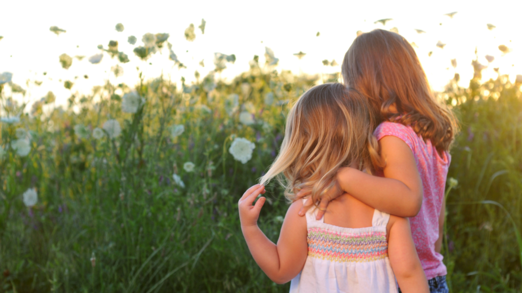 Two young girls with backs to camera facing field of flowers