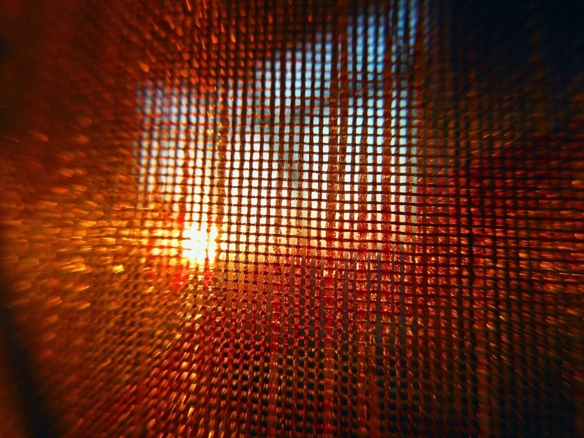 close up of window screen with bright sun shining through