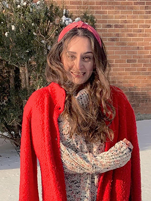 Author Headshot: Selina Mahmoud, a Pakistani American Woman, wearing a red coat.