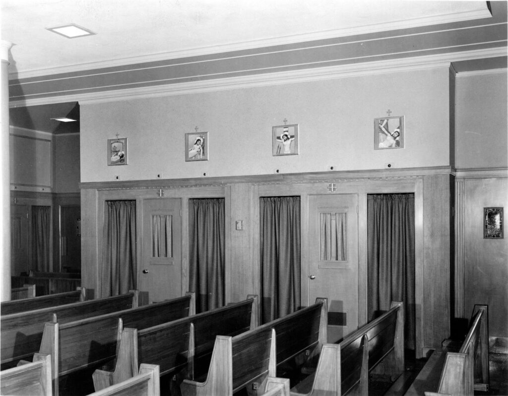 interior of catholic church with rows of pews and curtained confession booths