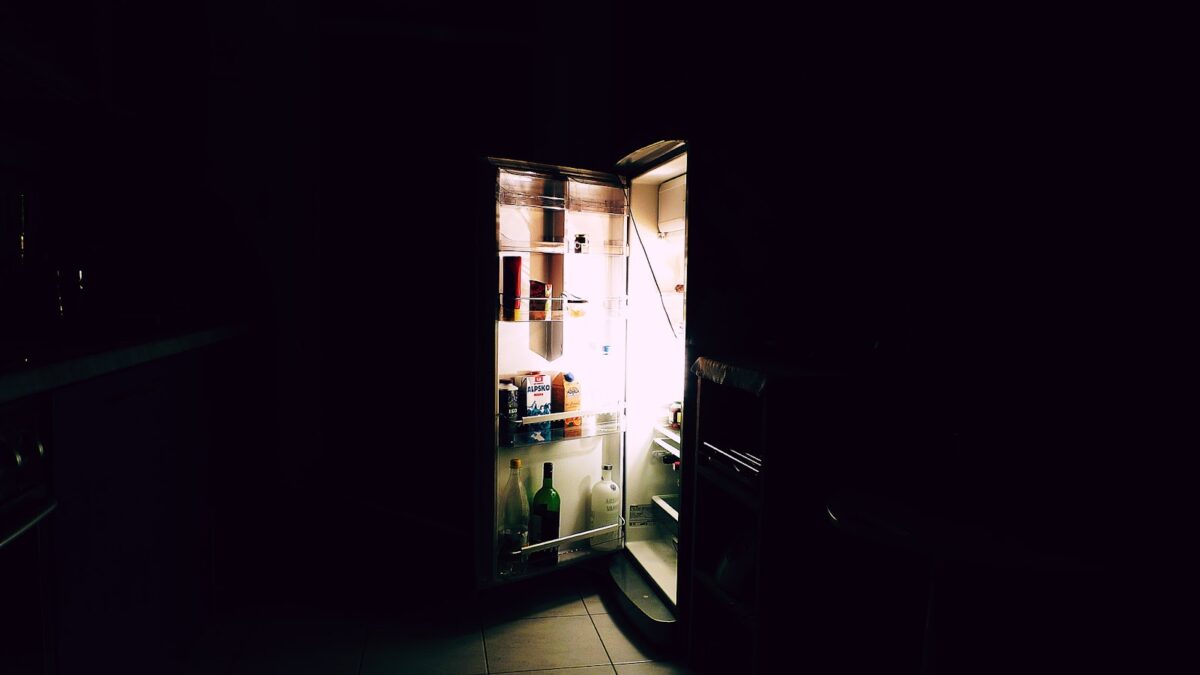 dark kitchen with fridge door open and light coming out - various items inside