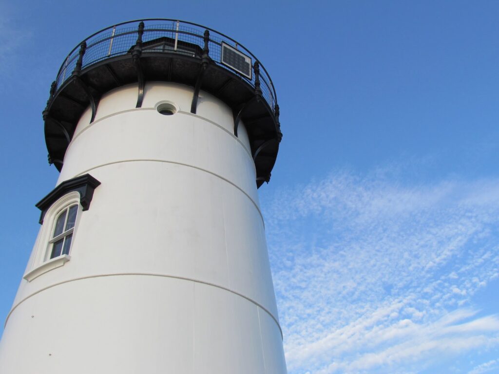 White lighthouse taken from below looking up at clear blue sky