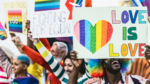 colorful "love is love" and other signs at a equality demonstration