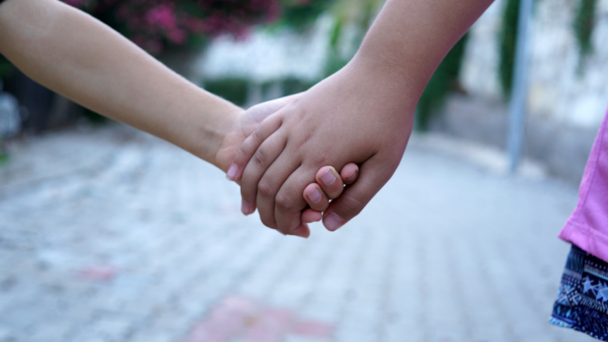 close-up of children holding hands (only held hands shown.)