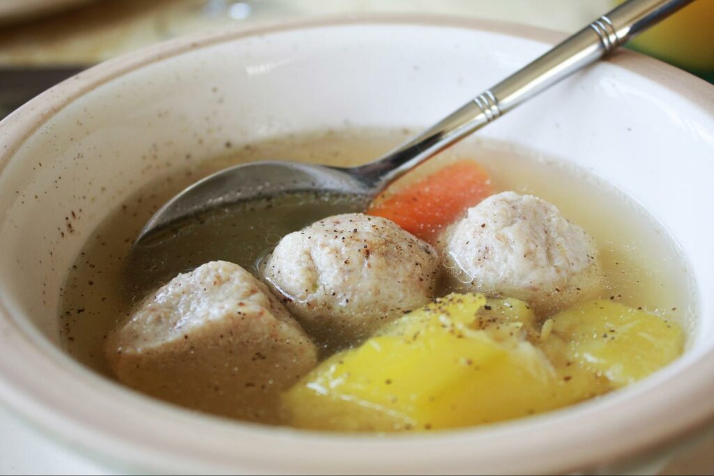 A bowl of matzo ball soup with a spoon
