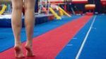 A close-up of a person's feet, standing on tip toe, on a gymnastic mat