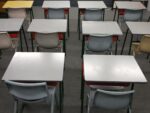 row of empty classroom desks and chairs; sterile vibe