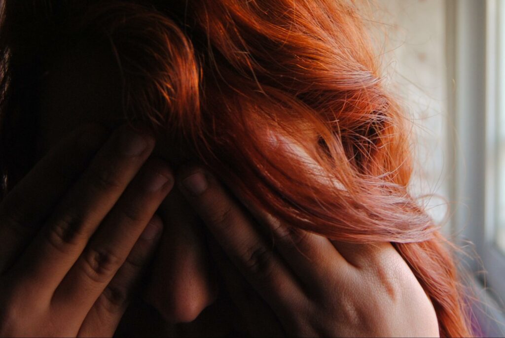 woman's face in hands and in red hair