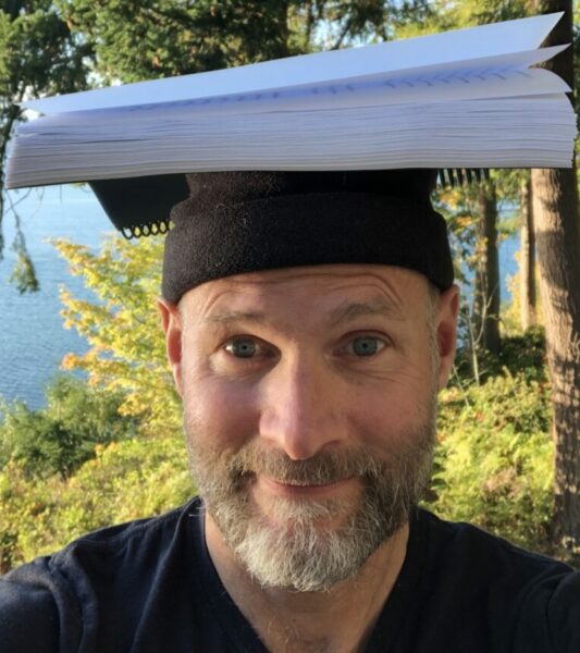 Craig Holt author photo, balancing manuscript on his head